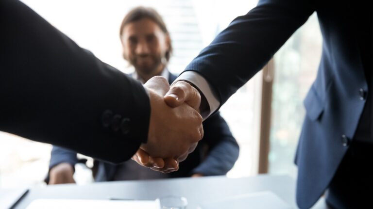 Two businessmen shake hands at a meeting