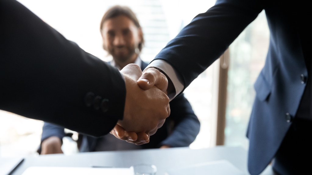 Two businessmen shake hands at a meeting